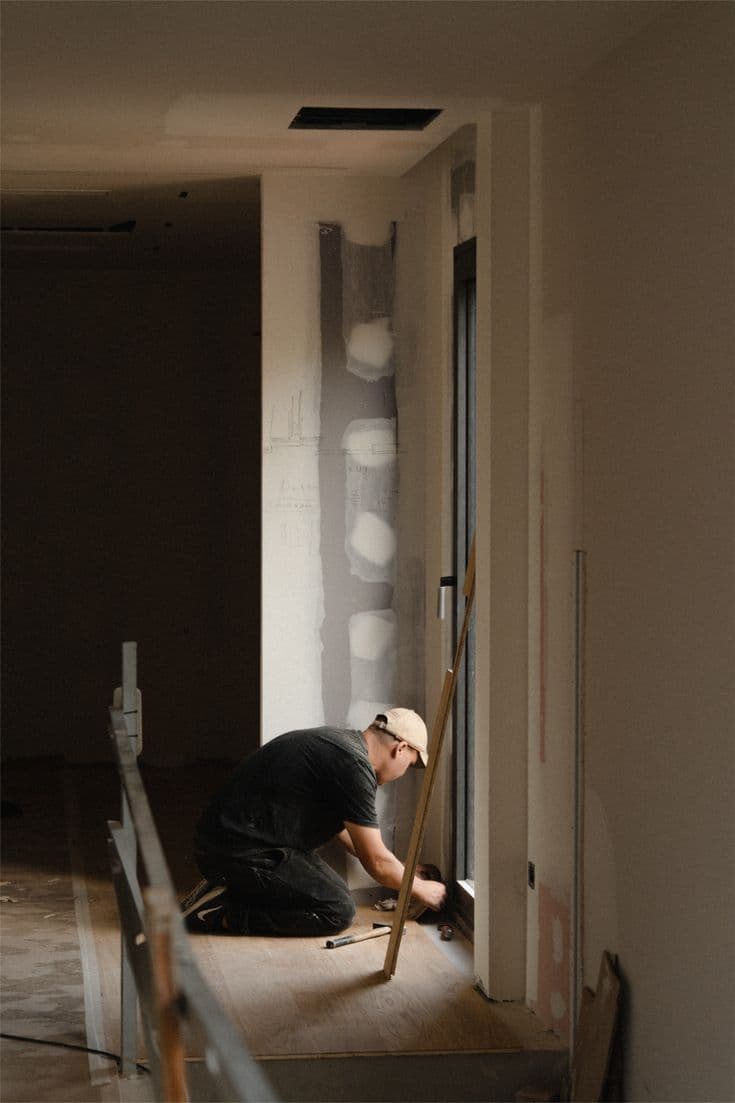 Bodenleger verlegt Parkett entlang einer Türschwelle