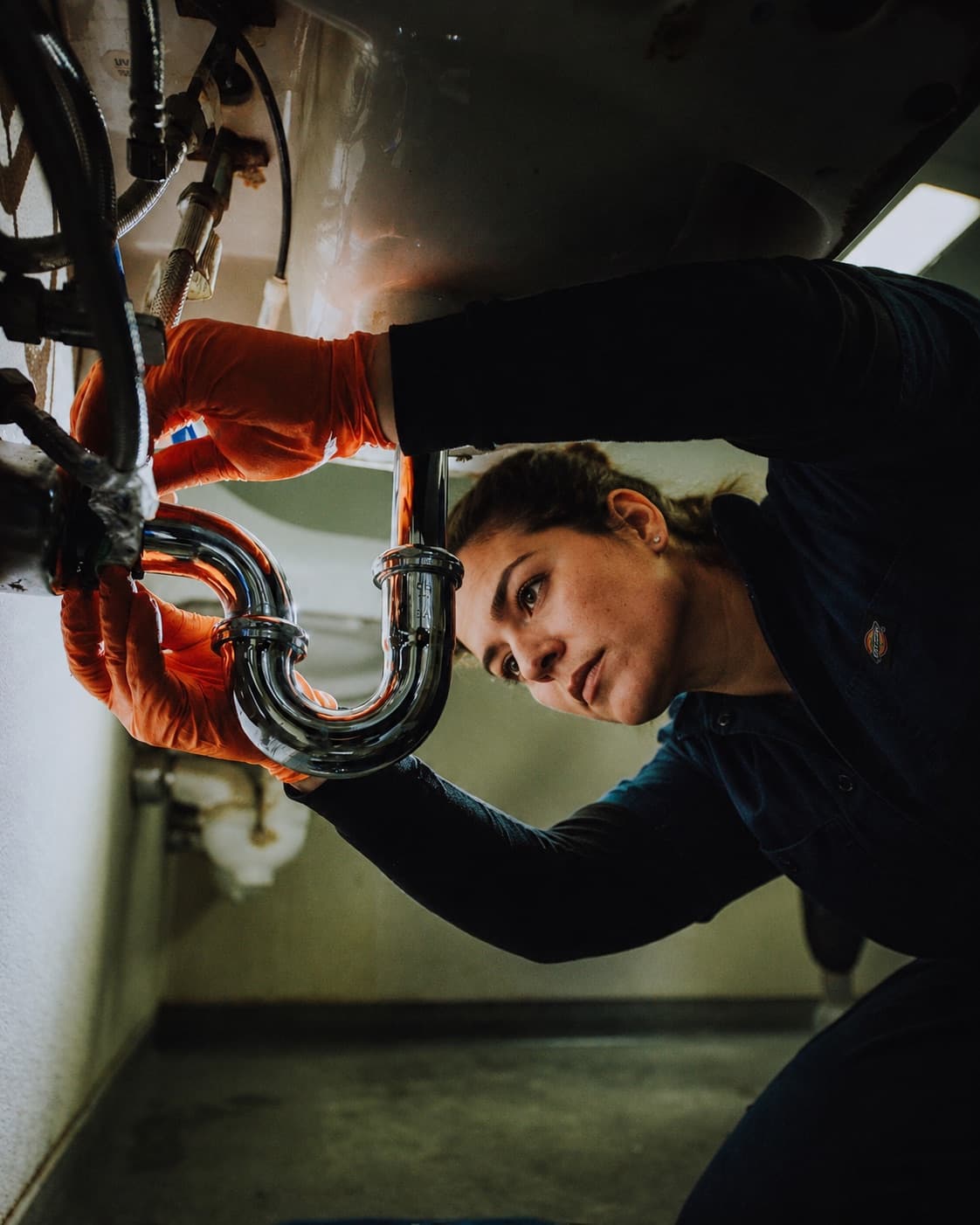 Sanitärmonteurin arbeitet am Siphon unter dem Waschbecken